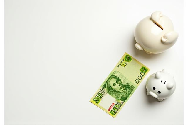 Dos billetes de pesos chilenos y una alcancía, con letras APV y DP, simbolizando opciones de inversión para el futuro.